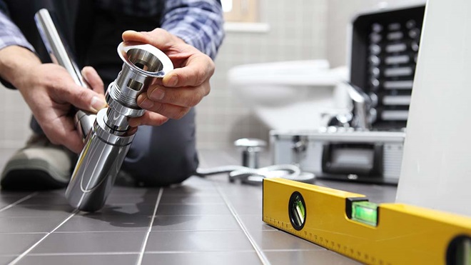 plumber installing pipe in bathroom